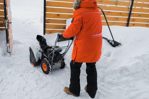 A man clear snow from backyard with snow blower. Winter season and snow blower equipment.