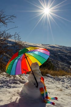 snowman with umbrella in lgtb pride colors, on a background of snowy mountains with starry sun and sky,