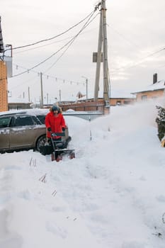 A man clear snow from backyard with snow blower. Winter season and snow blower equipment.