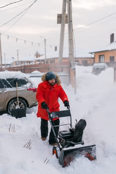 A man clear snow from backyard with snow blower. Winter season and snow blower equipment.