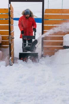 A man clear snow from backyard with snow blower. Winter season and snow blower equipment.