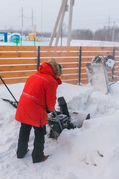 A man clear snow from backyard with snow blower. Winter season and snow blower equipment.