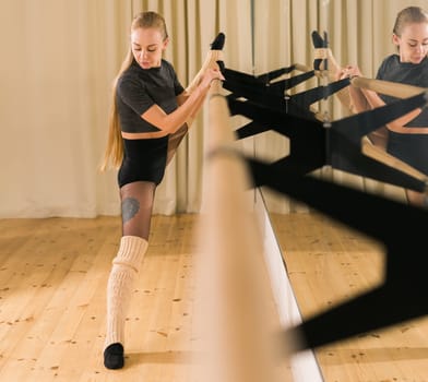 Female ballet dancer practicing at barre in dance studio - dance and ballerina