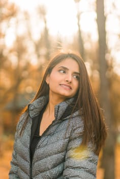 Close up portrait of pretty indian young woman enjoying warm autumn sunny day vacation outdoors. Generation z and gen z concept. Fall Season.