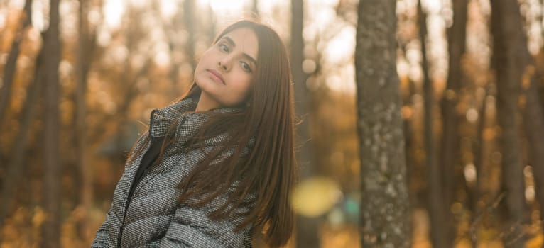 Beautiful indian woman generation z relaxing and feeling nature at autumn park in fall season. Diversity and gen z youth.