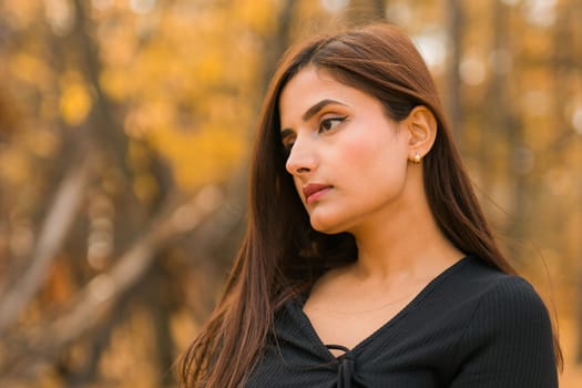 Close up portrait of pretty indian young woman enjoying warm autumn sunny day vacation outdoors. Generation z and gen z concept. Fall Season.