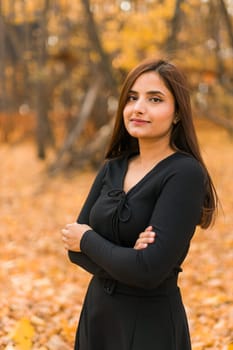 Close up portrait of pretty indian young woman enjoying warm autumn sunny day vacation outdoors. Generation z and gen z concept. Fall Season.