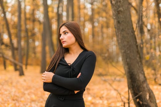 Close up portrait of pretty indian young woman enjoying warm autumn sunny day vacation outdoors. Generation z and gen z concept. Fall Season.