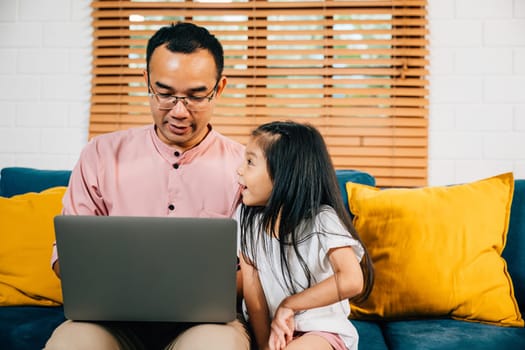 An Asian family enjoys quality time in their modern living room as the father works on his laptop and his daughter engages in e-learning on a computer. Their bonding smiles and happiness are evident.