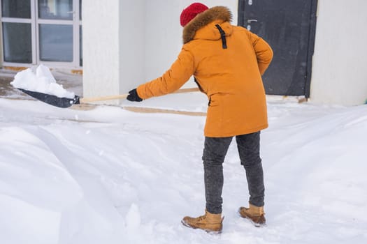 Man removing snow and ice from the sidewalk in front of house. Winter season.