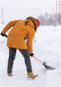 Man cleaning snow from sidewalk and using snow shovel. Winter season.