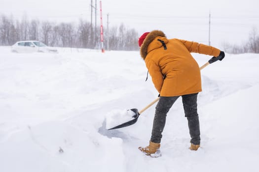 Man removing snow and ice from the sidewalk in front of house. Winter season.