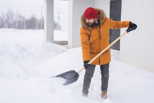 Man removing snow and ice from the sidewalk in front of house. Winter season.