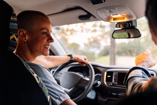 smiling woman driving his camper van through the countryside, concept of couple adventure travel and active tourism in nature