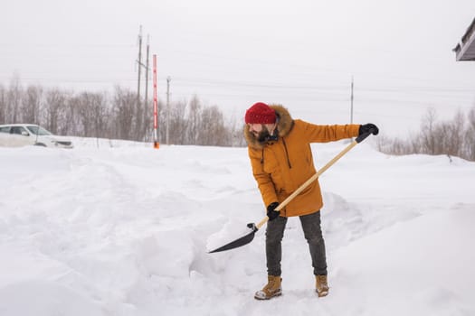 Man removing snow and ice from the sidewalk in front of house. Winter season.