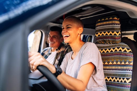 couple laughing happy during their route through the countryside in camper van, concept of adventure travel and active tourism in nature