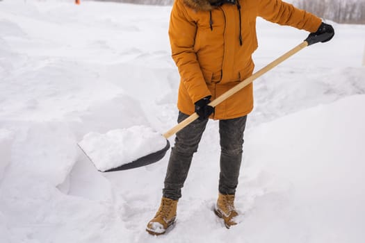 Young man clearing snow in his backyard village house with shovel. Remove snow from the sidewalk