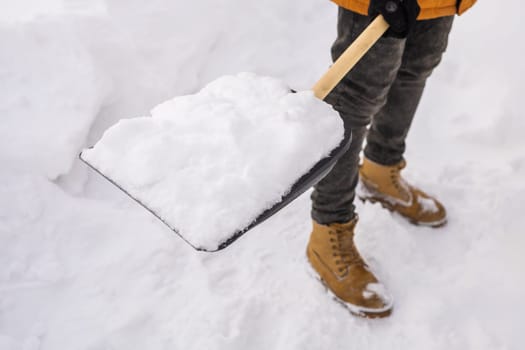 Man cleaning snow from sidewalk and using snow shovel. Winter season.