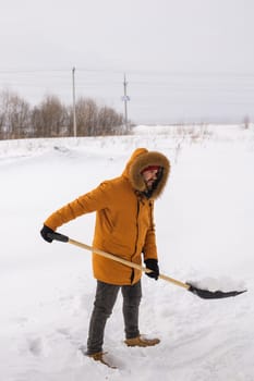 A man cleans and clears the snow in front of the house on frosty day. Cleaning the street from snow on a winter day. Snowfall and severe snowstorm in winter