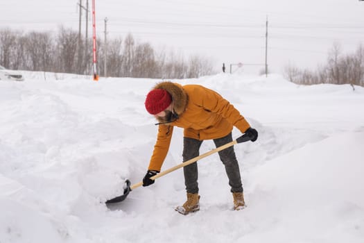 Man cleaning snow from sidewalk and using snow shovel. Winter season.