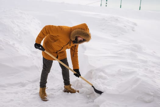 Man is clearing the snow near house and on staircases hovelling at the winter season. Winter storm and season specific.