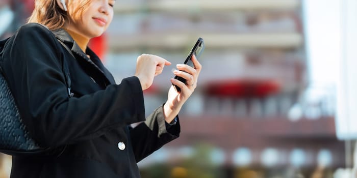 Successful business woman play mobile outdoor. beautiful woman going to working with smartphone walking near office building.