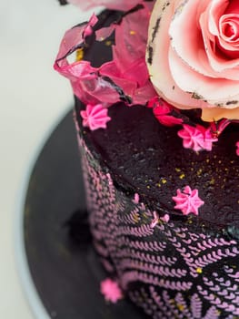 frosted icing black decorate cake for birthday celebration, real rose topping and pink sweet swirls studio isolated shot