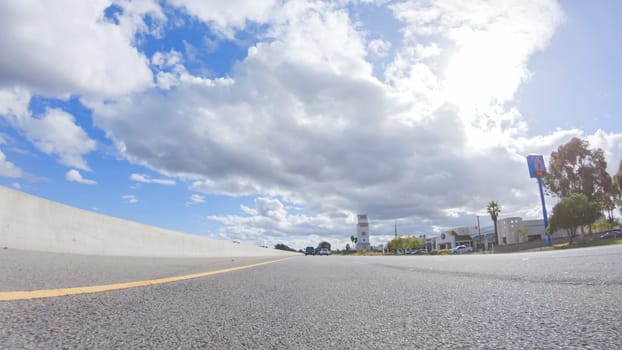 On a cloudy winter day, a car smoothly travels along Highway 101 near Santa Maria, California, under a cloudy sky, surrounded by a blend of greenery and golden hues.