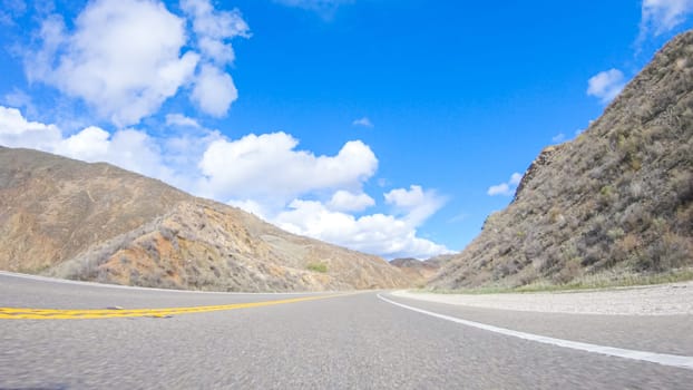 Vehicle is cruising along the Cuyama Highway under the bright sun. The surrounding landscape is illuminated by the radiant sunshine, creating a picturesque and inviting scene as the car travels through this captivating area.