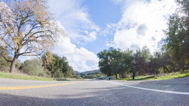 Vehicle is cruising along the Cuyama Highway under the bright sun. The surrounding landscape is illuminated by the radiant sunshine, creating a picturesque and inviting scene as the car travels through this captivating area.