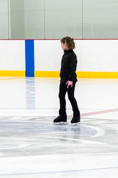 Little girl practicing figure skating at the indoor ice rink.