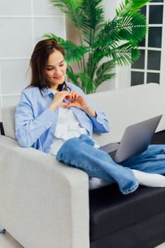 Woman working remotely on laptop from sofa at home