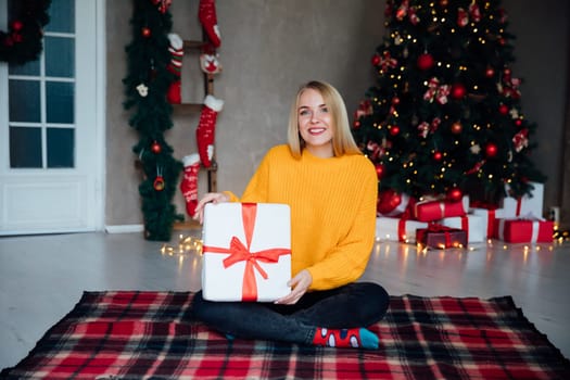 woman sitting in a room with a Christmas tree with a gift Holiday Christmas