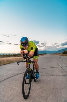 Triathlete riding his bicycle during sunset, preparing for a marathon. The warm colors of the sky provide a beautiful backdrop for his determined and focused effort