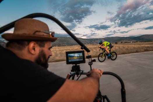 A videographer recording a triathlete riding his bike preparing for an upcoming marathon.Athlete's physical endurance and the dedication required to succeed in the sport