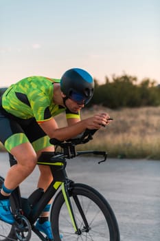 Triathlete riding his bicycle during sunset, preparing for a marathon. The warm colors of the sky provide a beautiful backdrop for his determined and focused effort