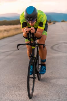 Triathlete riding his bicycle during sunset, preparing for a marathon. The warm colors of the sky provide a beautiful backdrop for his determined and focused effort