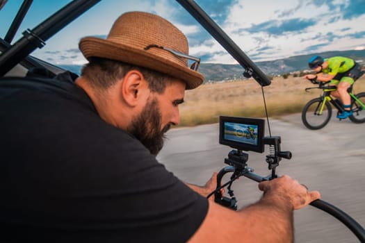 A videographer recording a triathlete riding his bike preparing for an upcoming marathon.Athlete's physical endurance and the dedication required to succeed in the sport