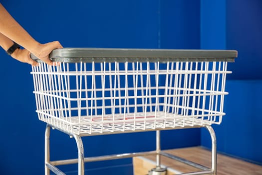 Laundromat convenience store. Woman hands holding empty new white trolley cart, metal cart parked use for laundry at convenience store for support customer