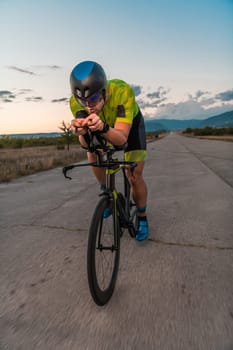 Triathlete riding his bicycle during sunset, preparing for a marathon. The warm colors of the sky provide a beautiful backdrop for his determined and focused effort