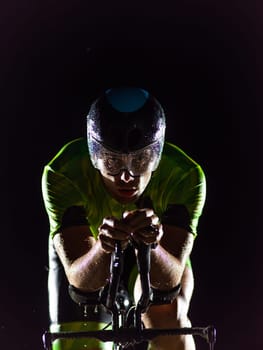 A triathlete rides his bike in the darkness of night, pushing himself to prepare for a marathon. The contrast between the darkness and the light of his bike creates a sense of drama and highlights the athlete's determination and perseverance