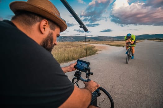 A videographer recording a triathlete riding his bike preparing for an upcoming marathon.Athlete's physical endurance and the dedication required to succeed in the sport