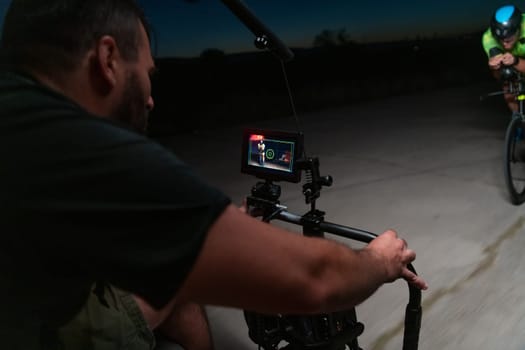 A videographer recording a triathlete riding his bike preparing for an upcoming marathon.Athlete's physical endurance and the dedication required to succeed in the sport