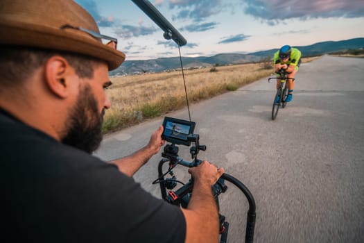 A videographer recording a triathlete riding his bike preparing for an upcoming marathon.Athlete's physical endurance and the dedication required to succeed in the sport