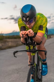 Triathlete riding his bicycle during sunset, preparing for a marathon. The warm colors of the sky provide a beautiful backdrop for his determined and focused effort