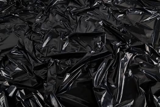 full-frame abstract background of crumpled black plastic film bag.