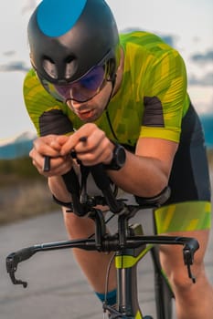 Triathlete riding his bicycle during sunset, preparing for a marathon. The warm colors of the sky provide a beautiful backdrop for his determined and focused effort