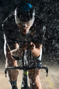 A triathlete braving the rain as he cycles through the night, preparing himself for the upcoming marathon. The blurred raindrops in the foreground and the dark, moody atmosphere in the background add to the sense of determination and grit shown by the athlete