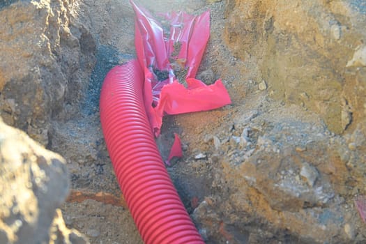 Cables in the trench. High-voltage cables in a protective covering in an excavation. Concept of electrical installations, construction works, building renovations and building refurbishments.