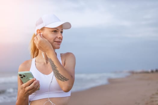 Running woman. Female runner with her smartphone training outdoor workout on beach. Beautiful fit Fitness model outdoors. High quality photo.